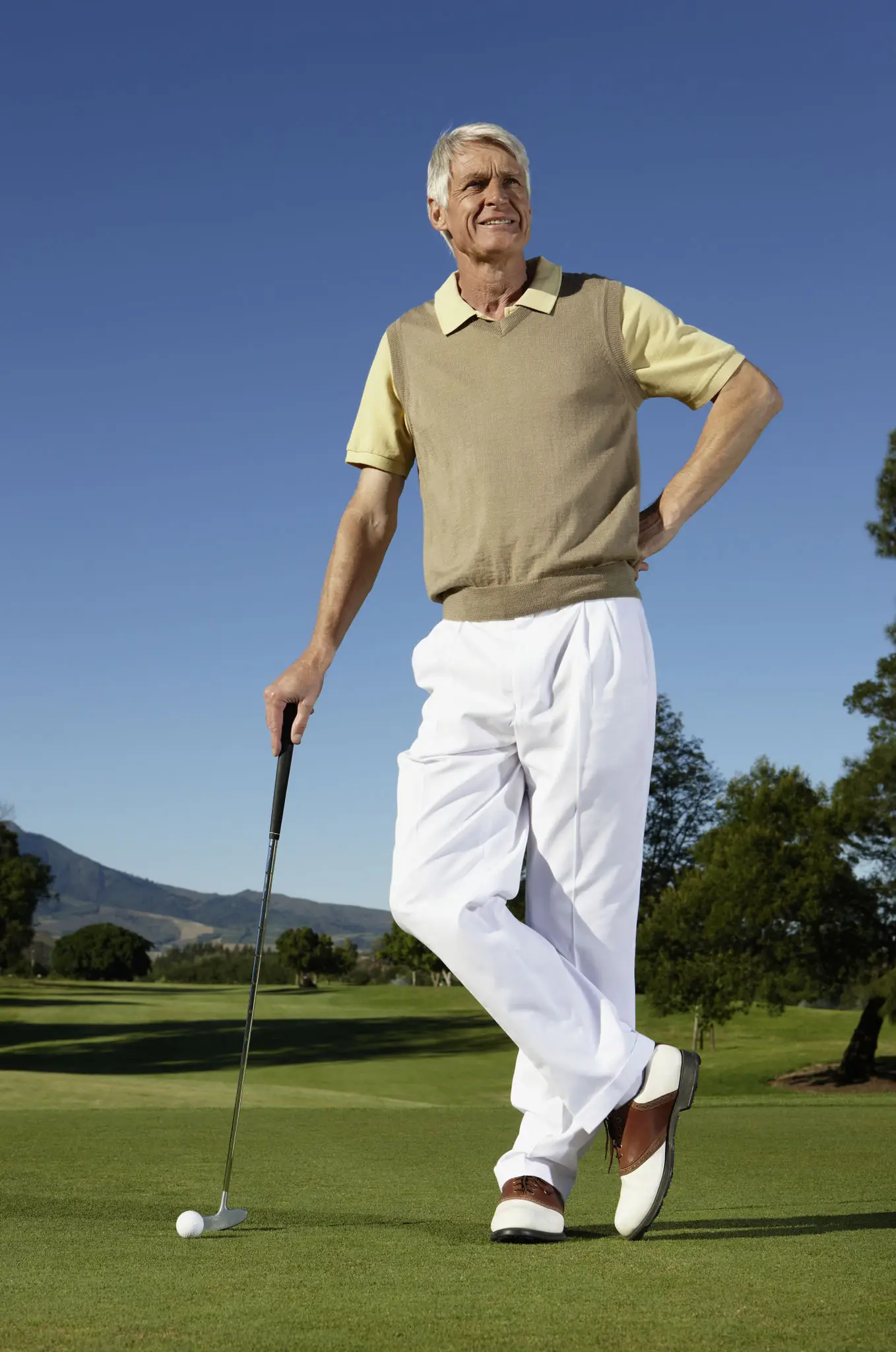 A man in golf attire standing on a golf course with a club.